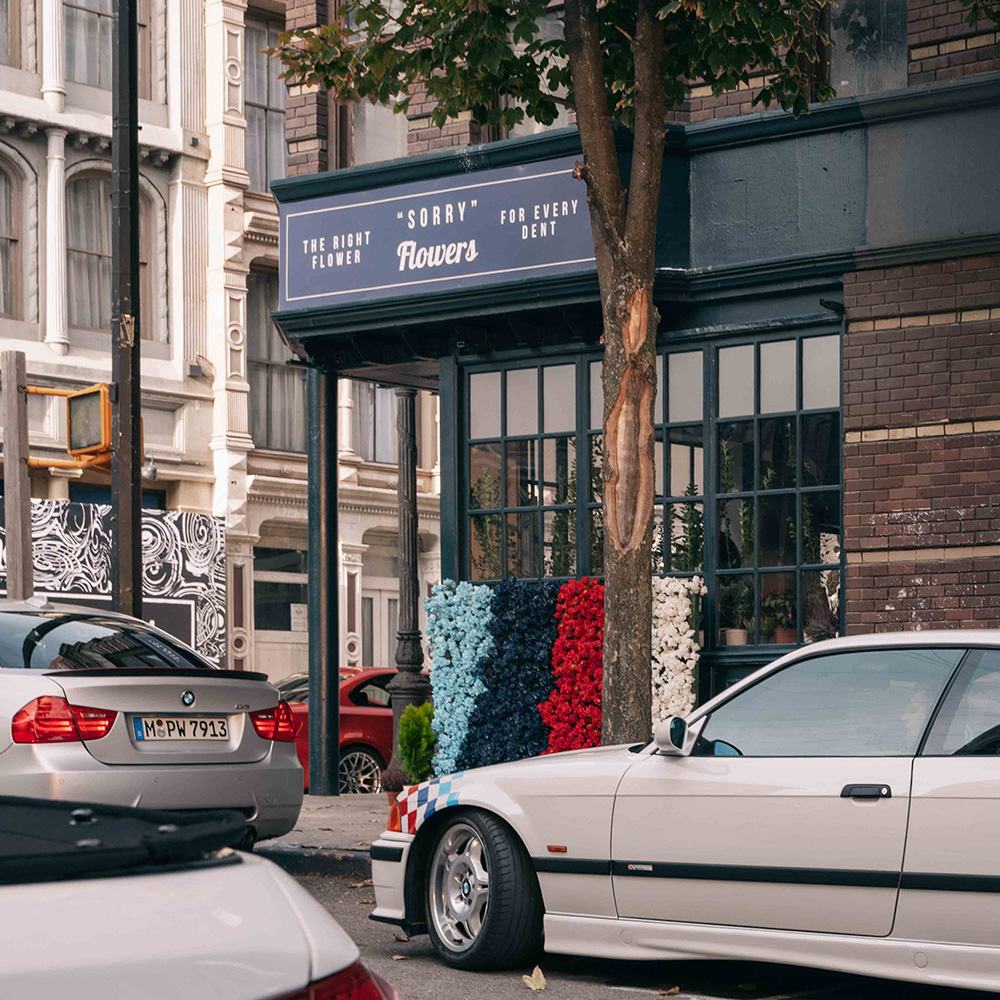 Flower store facade with Sorry For Every Bone sign and classic BMW