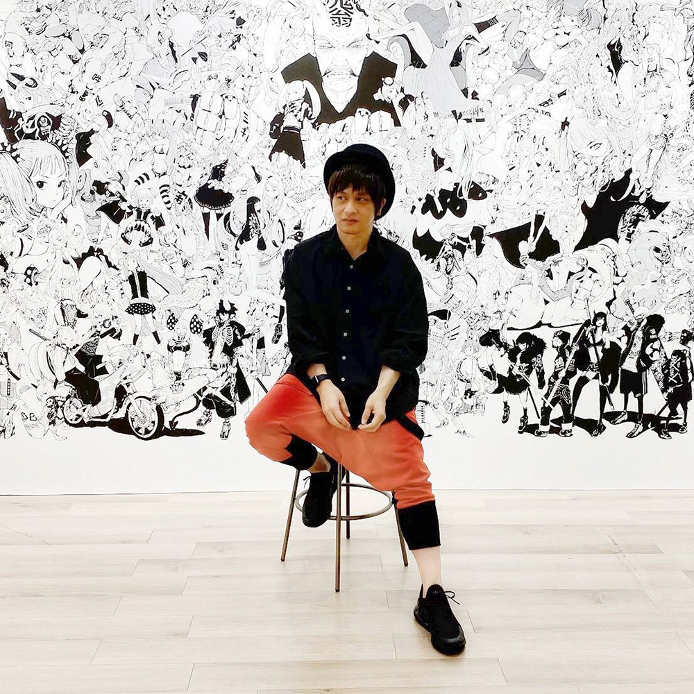 Japanese manga artist Acky Bright posing in front of his artwork